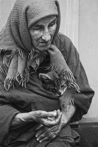 Cидела у подъезда на скамейке, Помятая, в разбитых башмаках Бездомная старушка в телогрейке С котёночком приблудным на руках.